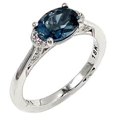 a ring with an oval blue stone and diamonds on the band, set in white gold