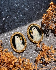 two buttons with ghost pictures on them sitting in front of some grass and dirt,