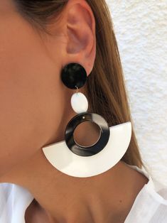 a woman wearing black and white earrings with an oval design on the bottom of her ear