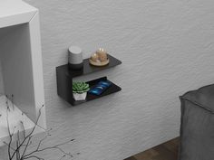 two black shelves on the wall near a chair and potted plant in a vase