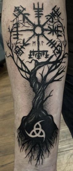 a man's leg with a tree and compass tattoo on it