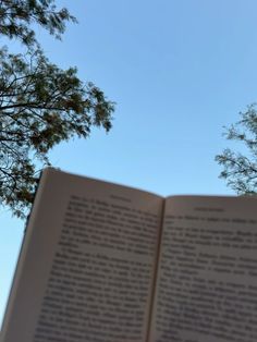 an open book sitting in front of a tree