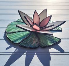 a glass flower sitting on top of a green leaf