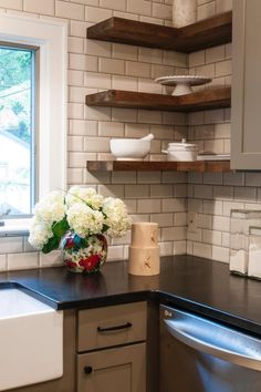 an image of a kitchen with white flowers on the counter and shelving above it