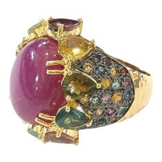 This is part of Chairish’s Fine Jewelry assortment.  Center Oval Shape Natural Ruby - 4 Carat  Multi color Natural Sapphires from Sri Lanka 2.50 Carat  Round and Pear shape Brilliant Colors: Pink, Yellow, Rose, Green and Blue   This Ring is from the "Orient" traveling collection are the epitome of elegance and versatility. It offers a perfect blend of day to night and swimwear to evening wear, allowing you to effortlessly transition between different occasions and outfits.  Wearing these spectac Luxury Ruby Cabochon Diamond Ring, Formal Multicolor Diamond Gemstones, Elegant Multicolor Cabochon Rings, Luxury Multicolor Ruby Ring, Multicolor Cabochon Rings For Formal Occasions, Luxury Ruby Ring With Diamond Accents, Elegant Multicolor Cabochon Gemstones, Formal Multicolor Cabochon Rings, Luxury Multicolor Cabochon Rings