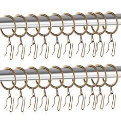 several pairs of metal hooks hanging from the side of a curtain rod on a white background