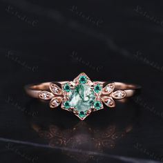 an engagement ring with green and white stones on the side, set in rose gold