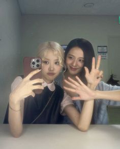 two young women posing for a photo with their hands up in front of the camera