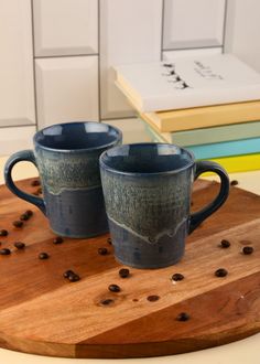 two coffee mugs sitting on top of a wooden board