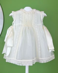 An elegant and delicate off-white dress with a geometrical smock detail and laces. It comes with a matching bonnet, and the dress has buttons on the back for closure. Made in Spain Dry clean Final sale, no exchanges nor returns are accepted White A-line Dresses With Lace Collar, White A-line Vintage Dress With Ruffles, Classic Daywear Dresses With Smocked Back, Classic Dresses With Smocked Back For Daywear, Classic White Lined Dress, Ceremony Dress With Lace Trim And Fitted Bodice, Ceremonial Dress With Lace Trim And Fitted Bodice, Cream A-line Daywear Dress, Elegant Off-white Baptism Dress With Ruffles