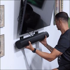 a man is working on a flat screen tv mounted to the wall with an extension rod