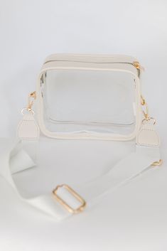 If you're a girl who is always on the go, then the Energetic Aesthetic Clear Crossbody Bag is crucial for stylish success! This chic handbag is designed with a faux leather trim and a clear body. It features a functional zipper closure and a knit removable adjustable crossbody strap. Use the Energetic Aesthetic Clear Crossbody Bag for game days! Available in 2 colors. Faux Leather Trim Clear Body Gold Hardware Removable Adjustable Crossbody Strap Functional Zipper Closure One Size | Length 5" | Energetic Aesthetic, Chic Handbags, Store Hours, Bag Dress, Black Cross Body Bag, Ivory Color, Crossbody Strap, Leather Trim, Leather Trims