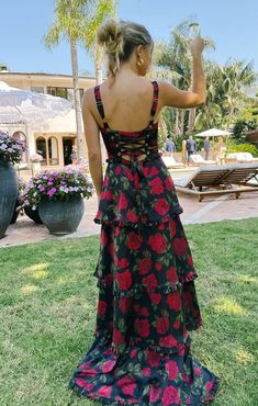 a woman standing in the grass with her back to the camera and wearing a floral dress