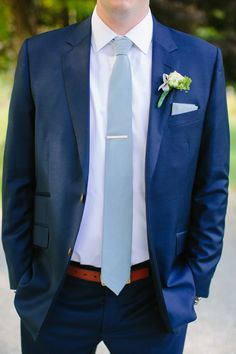 a man wearing a blue suit and tie with a flower in his lapel pocket