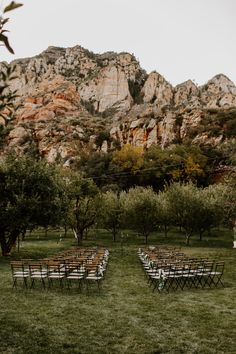 rows of chairs set up in the grass for an outdoor ceremony with mountains in the background