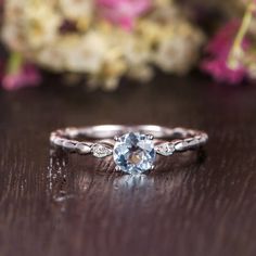 a close up of a ring on a wooden table with flowers in the back ground