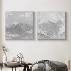 two paintings are hanging on the wall above a round coffee table in a living room