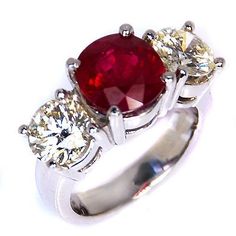 three stone engagement ring with red and white stones on the sides, set in 18k white gold