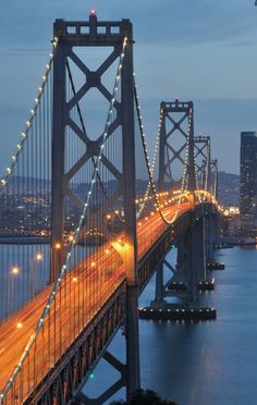 a long bridge that is over water with lights on at the top and below it