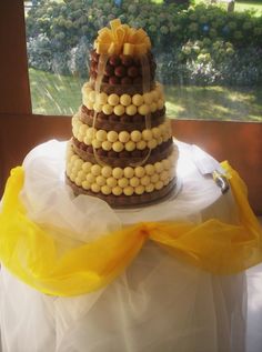 a three tiered cake with chocolate and white candies on the top is sitting on a table