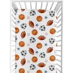 a crib bed with soccer and basketballs on the sheets in orange, white and blue