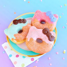 three donuts with frosting and sprinkles are on a blue and yellow plate