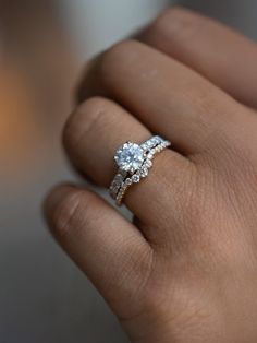 a woman's hand with a diamond ring on top of her finger and an engagement band