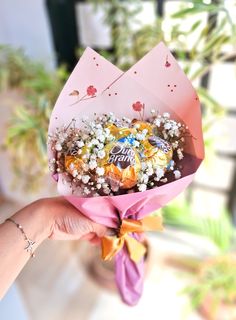 a person holding a bouquet of flowers and chocolates in it's wrapper