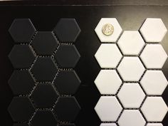 some black and white hexagonal tiles are next to a gold coin on a table