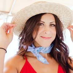 a woman wearing a straw hat and red top with a blue scarf around her neck