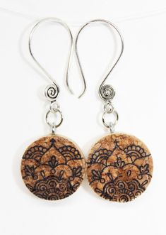 pair of earrings with brown and black designs on them, hanging from silver earwires