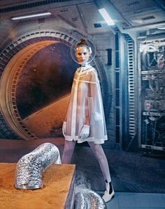 a mannequin wearing a clear coat and silver shoes in front of a tunnel