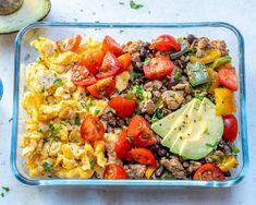 a glass dish filled with scrambled eggs, tomatoes and avocado