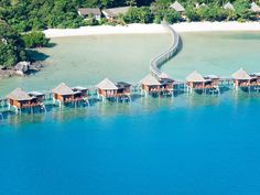 an aerial view of some huts in the water with a walkway leading up to them