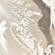 white lace with flowers and leaves is shown on a sheer fabric, as well as the shadow of a woman's head