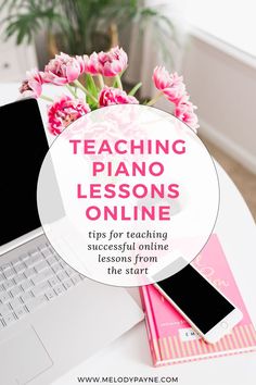 a laptop computer sitting on top of a white table next to pink flowers and books