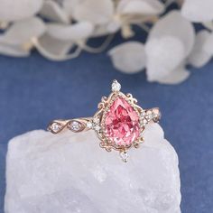 a pink diamond ring sitting on top of a rock