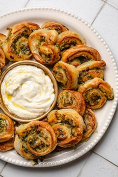 a white plate topped with different types of pastries next to a bowl of sour cream