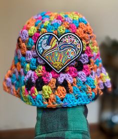 a multicolored crocheted hat with a heart patch