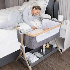 a woman laying on top of a bed next to a baby in a crib