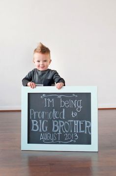 a little boy holding up a sign that says i'm being provided by big brother august 2013