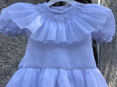 White smocked dress. Fully lined and ties on the back. Will be an appropriate dress for a flower girl, Christening or confirmation. Two are available SIZE 2T SIZE 6T For custom orders allow 2-3 weeks for delivery. Fitted Smock Wedding Dress, Elegant Baptism Dress With Smocked Back, Elegant Dress With Smocked Back For Baptism, Elegant Summer First Communion Dress, Elegant Smocked Dresses For Baptism, Elegant Smocked Ruffle Dress For Baptism, Elegant First Communion Dress For Summer Confirmation, Elegant Smock Dresses For Baptism, Elegant Smock Wedding Dress