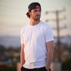 a man in white shirt and black shorts standing next to a pole with his hands on his hips