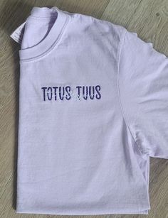 "This Listing is for our Totus Tuus, Totally Yours, embroidered Catholic t-shirt. It is a beautiful Marian t-shirt; in Latin, the phrase, \"Totus Tuus,\" means \"totally yours\", a motto from JPII, who had a great devotion to our blessed Mother.  When placing your order, in the personalization box, please include the following information: 1.) Two Thread colors (one for \"TOTUS TUUS\" and one for \"Totally Yours\" If no thread color is entered, we will automatically use colors as shown in the sa Catholic T Shirt, Purple Cotton Tops With Embroidered Text, Casual Short Sleeve Shirt With Letter Embroidery, Pocket Oratory, Catholic Tshirt, Catholic Clothing, Catholic Shirt, Catholic Tshirts, Minimalist Shirts