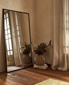 a mirror sitting on top of a wooden floor next to a planter filled with flowers