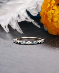 an image of a wedding band with blue topaz stones on the side and flowers in the background