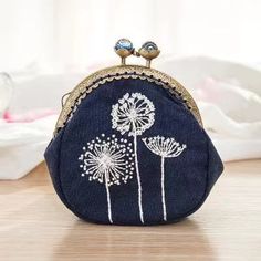 a blue purse with dandelions on it sitting on a wooden table next to a white cloth