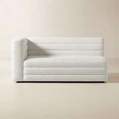 a white couch sitting on top of a floor next to a beige wall in an empty room