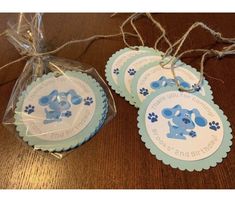 three tags with blue dogs on them sitting on a wooden table next to twine of twine