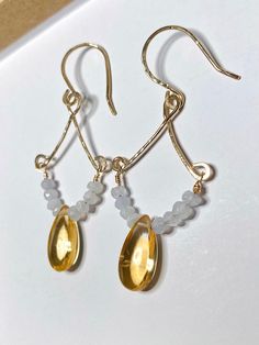 These earrings feature genuine citrine with blue lace agate accent beads. All metal components are 12K gold-filled. Handcrafted with love.  Details: -Materials: 12K gold-filled wire, citrine gemstones (heat-treated, ~7mmx14mm), and blue lace agate gemstones (~2-3mm).  -Drop length is approximately 2" -Appearance may vary slightly from sample images/videos. Each gemstone is unique and will vary in color/appearance. Gemstones: -Citrine: Believed by some to be a stone of joy, confidence, and abundance.  -Blue lace agate: Believed by some to support peace, clarity, and communication skills. Important Info.: -All earring sales are final, for hygienic reasons. If you have any issues with an item, please reach out via Etsy messages. -Small parts are a choking hazard for small children. THIS PRODU Adjustable Gold Chalcedony Jewelry, Gold Gemstone Bead Drop Earrings, Gold Drop Earrings With Gemstone Beads, Chalcedony Dangle Earrings With Natural Stones, Handmade Teardrop Chalcedony Jewelry, Chalcedony Dangle Earrings With Matching Jewelry, Chalcedony Dangle Jewelry With Matching Earrings, Gold Teardrop Earrings With Gemstone Beads, Gold Teardrop Earrings With Gemstone Accents